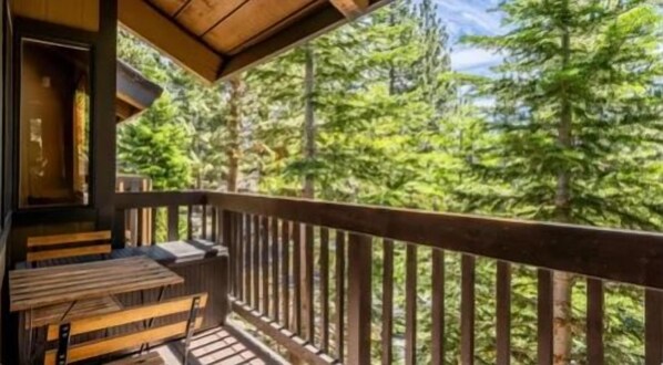 Une terrasse en bois, dotée de bancs, qui offre une vue sur une zone boisée.