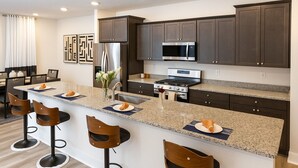 A modern kitchen with dark cabinets, stainless steel appliances, and a granite countertop. - Lux Escape w/King Bed/Loft/Skyline Views near BLT (Woodlawn)