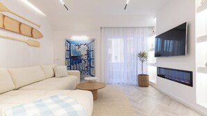 Un salon moderne avec un canapé, une table basse, une cheminée et un téléviseur fixé au mur.