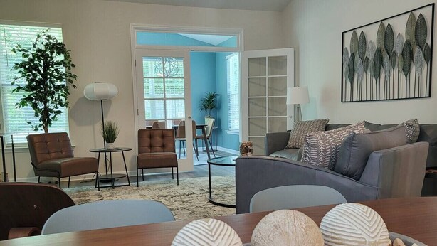 Un salon moderne avec une table basse en bois, un canapé gris et un coin repas avec des chaises.