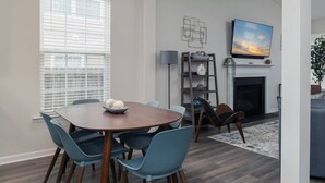 Un coin repas avec une table ronde et des chaises bleues, une cheminée et un téléviseur fixé au-dessus.
