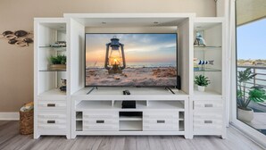 Una sala de estar moderna con un televisor de pantalla plana montado en un mueble blanco, rodeado de estanterías y cajones.