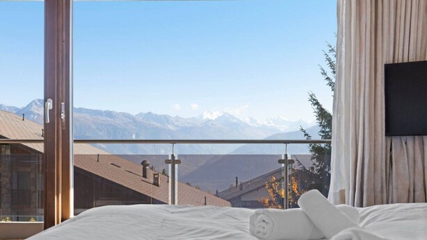 A bedroom with a large window overlooking a mountain range. - Crans-Montana, 5 pers : balcon vue & parking privé (Crans-Montana)