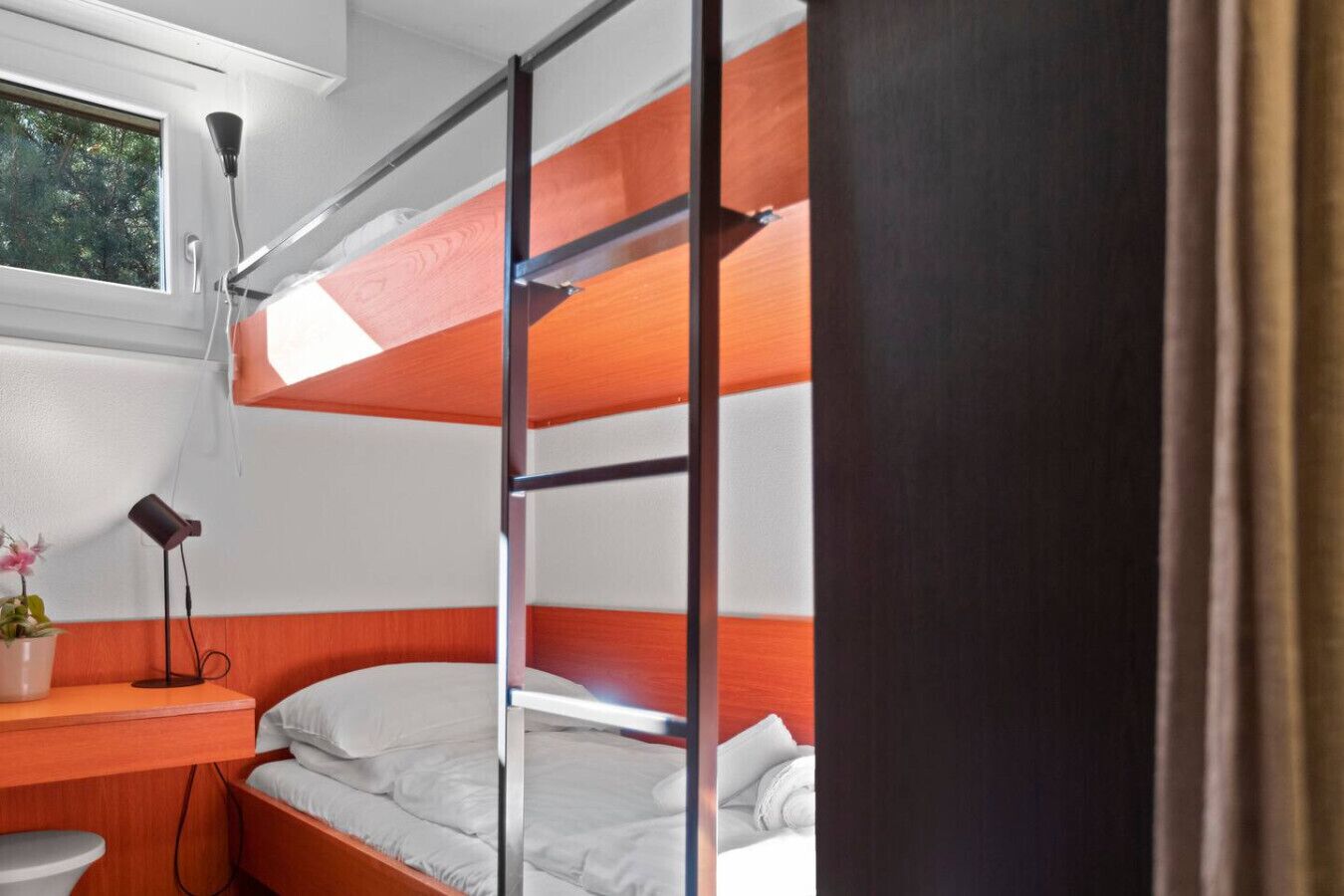 Une chambre avec un lit superposé, un bureau, une lampe et une plante en pot.