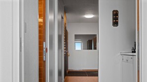 A narrow hallway with a wooden floor, white walls, and a door on the right. - Crans-Montana, 5 pers : balcon vue & parking privé (Crans-Montana)