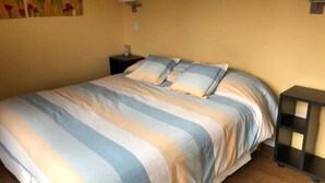 A bed with striped bedding, a bedside table, a lamp, and a wall-mounted shelf. - Upstairs apartment - Seeblick Bariloche (San Carlos de Bariloche)