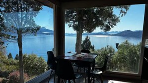 A dining area with a table and chairs, large windows offering a view of a lake and mountains. - Upstairs apartment - Seeblick Bariloche (San Carlos de Bariloche)
