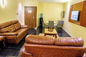 A hotel lobby with leather sofas, a small table, a water dispenser, and a TV mounted on the wall. - Villa Hilton Hotels & Apartments (Uyo)