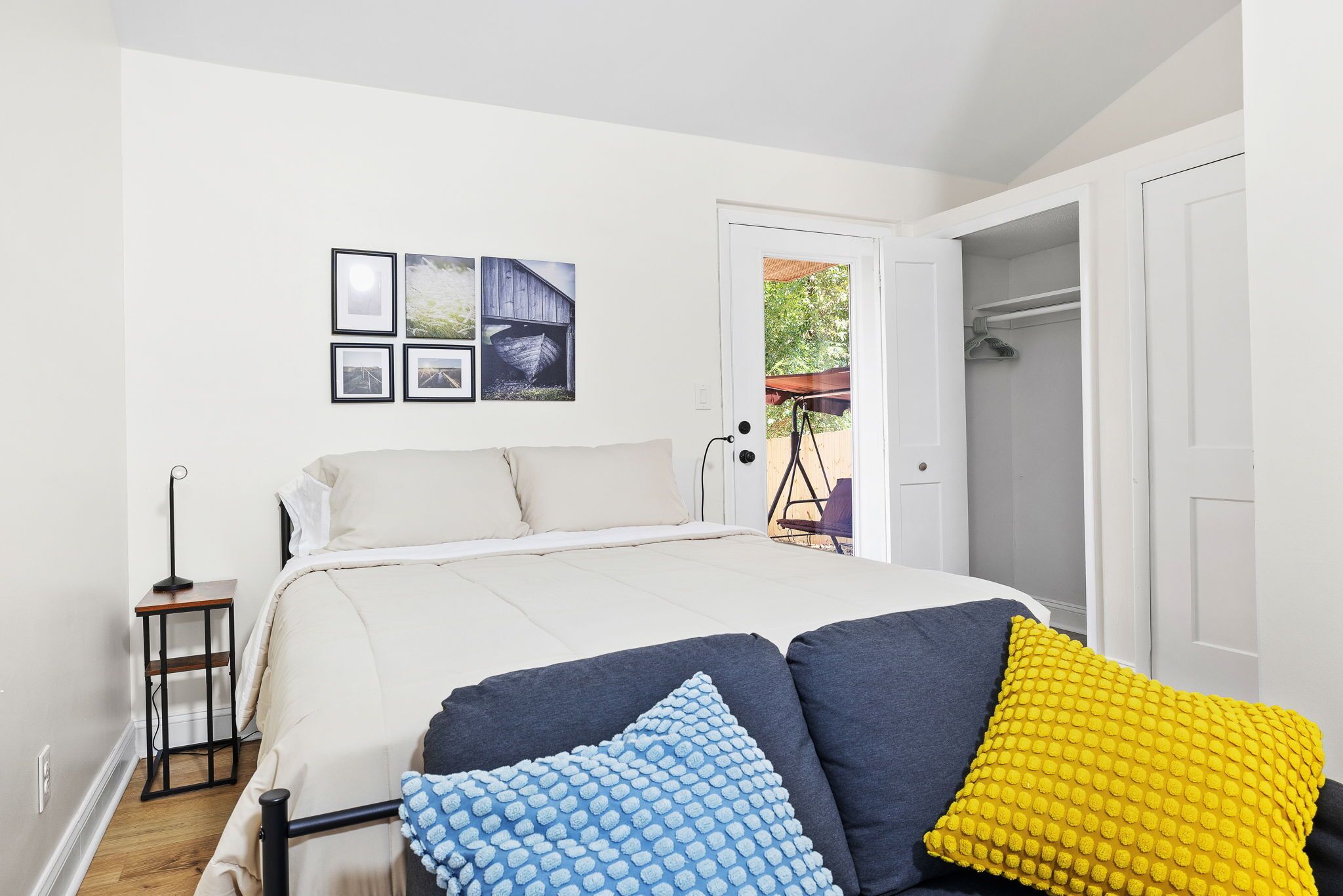 Una camera da letto con un letto, un comodino, una sedia e una porta che dà su uno spazio esterno.