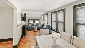 A modern living room with a sofa, a dining table with a vase of flowers, and a kitchen area in the background. - Stylish Retreat in DT Libertyville Near Naval Base (Libertyville)