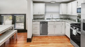 A compact kitchen with white cabinets, a stainless steel stove, and a dishwasher. - Stylish Retreat in DT Libertyville Near Naval Base (Libertyville)