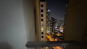A nighttime cityscape view from a balcony with a railing, featuring tall buildings and illuminated streets. - Casa Nova (Dubai)