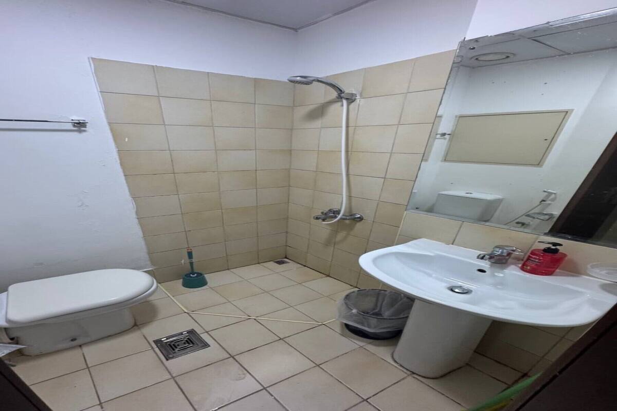 A small bathroom with a toilet, sink, shower, and mirror.