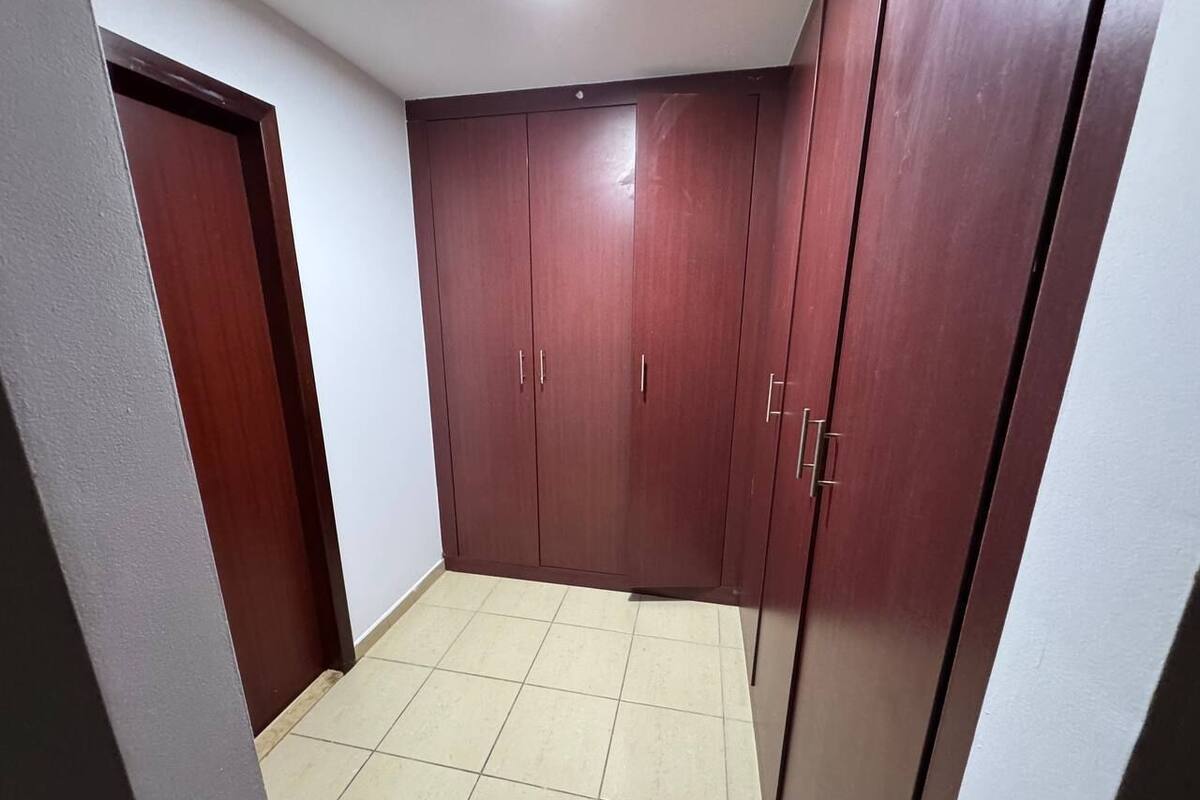A room with a tiled floor and wooden wardrobe with multiple doors.
