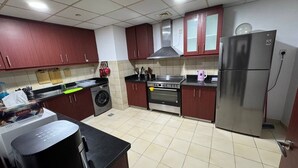 A kitchen with a washing machine, a stove, a refrigerator, and cabinets. - Casa Nova (Dubai)