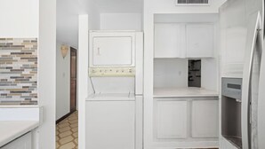 A compact kitchen with white cabinets, a built-in oven, and a refrigerator. - Oceanfront Terrace Communal Pool AC (Carolina)