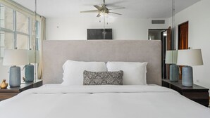 A modern hotel room with a large bed, a ceiling fan, and two bedside tables with lamps. - Oceanfront Terrace Communal Pool AC (Carolina)