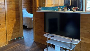 A wooden cabin interior with a kitchenette, a bed, and a TV. - Rustic UP Waterfront Cabin on Huron Bay (L'Anse)