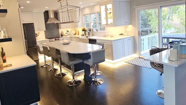A modern kitchen with a central island, white cabinetry, and a dark floor. - Luxurious Lakefront Retreat –  Sleeps 11 (Newtown)