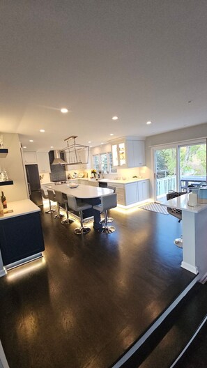 A modern kitchen with a central island, white cabinetry, and a dark floor. - Luxurious Lakefront Retreat – Sleeps 11 (Newtown)