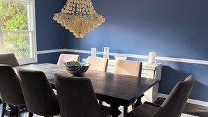 A dining room with a dark wooden table, six chairs, and a chandelier. - Luxurious Lakefront Retreat –  Sleeps 11 (Newtown)