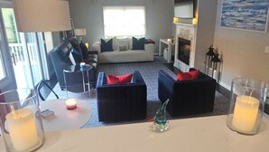 A living room with a sofa, two armchairs, a coffee table, and a fireplace. There are candles on the coffee table and a painting on the wall. - Luxurious Lakefront Retreat –  Sleeps 11 (Newtown)