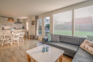A modern living room with a grey sofa, a coffee table, and a dining area with a white table and chairs.