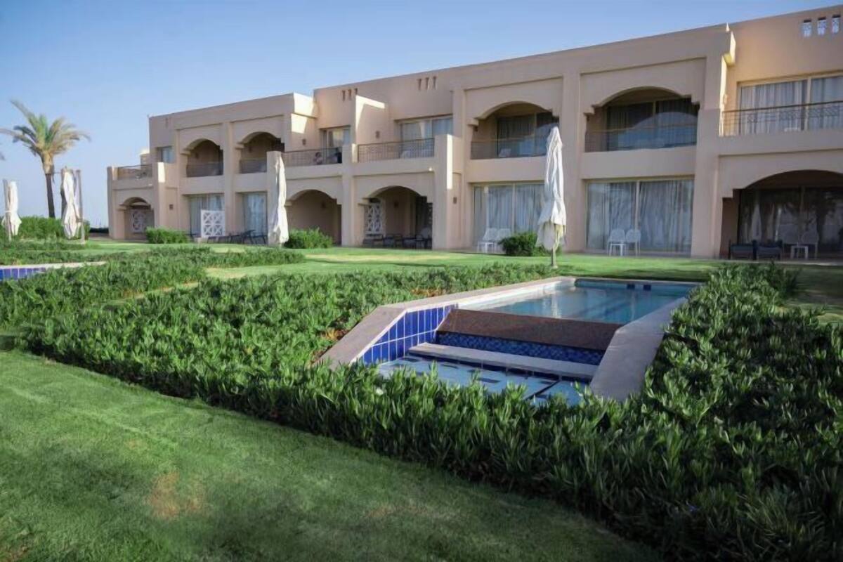 A hotel with a pool, multiple balconies, and well-maintained gardens.