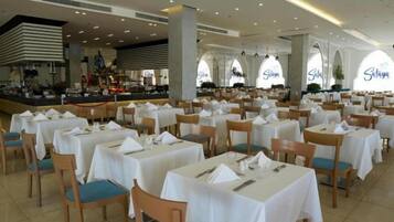 A spacious dining area with multiple tables and chairs, a central bar area, and large windows with the name 'Salah' visible.