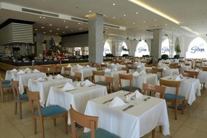 Ruime eetruimte met meerdere tafels en stoelen, een centraal gelegen bar en grote ramen, met de naam 'Salah' zichtbaar.