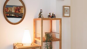 Una stanza con un mobiletto a mensole in legno, uno specchio e una lampada.