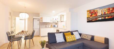 A modern apartment with a dining area, kitchen, and living room.