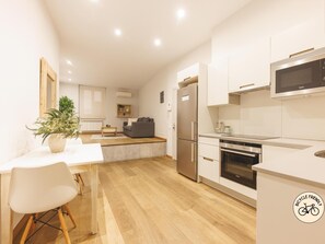 A modern kitchen with white cabinetry, a built-in oven, and a stainless steel refrigerator.