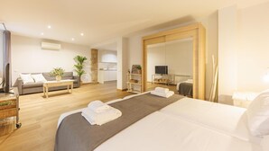 Una moderna camera d'albergo con un letto grande, una poltrona, un angolo cottura e uno specchio ampio.