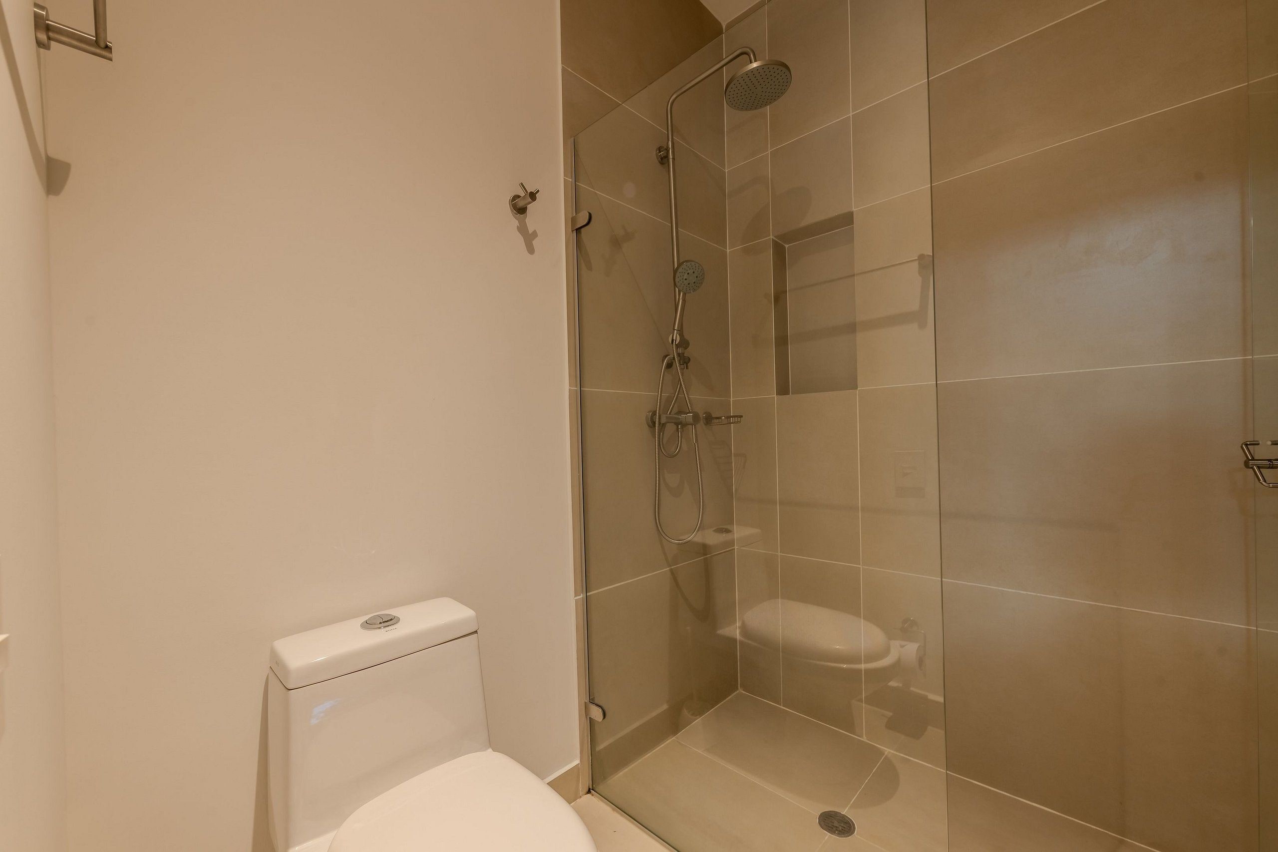 A bathroom with a toilet, a shower enclosure, and a glass door.