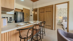 A modern kitchen with a central island, bar stools, wooden cabinets, and a wooden ceiling. - Apartamento premium en Baia Kristal (Cartagena)