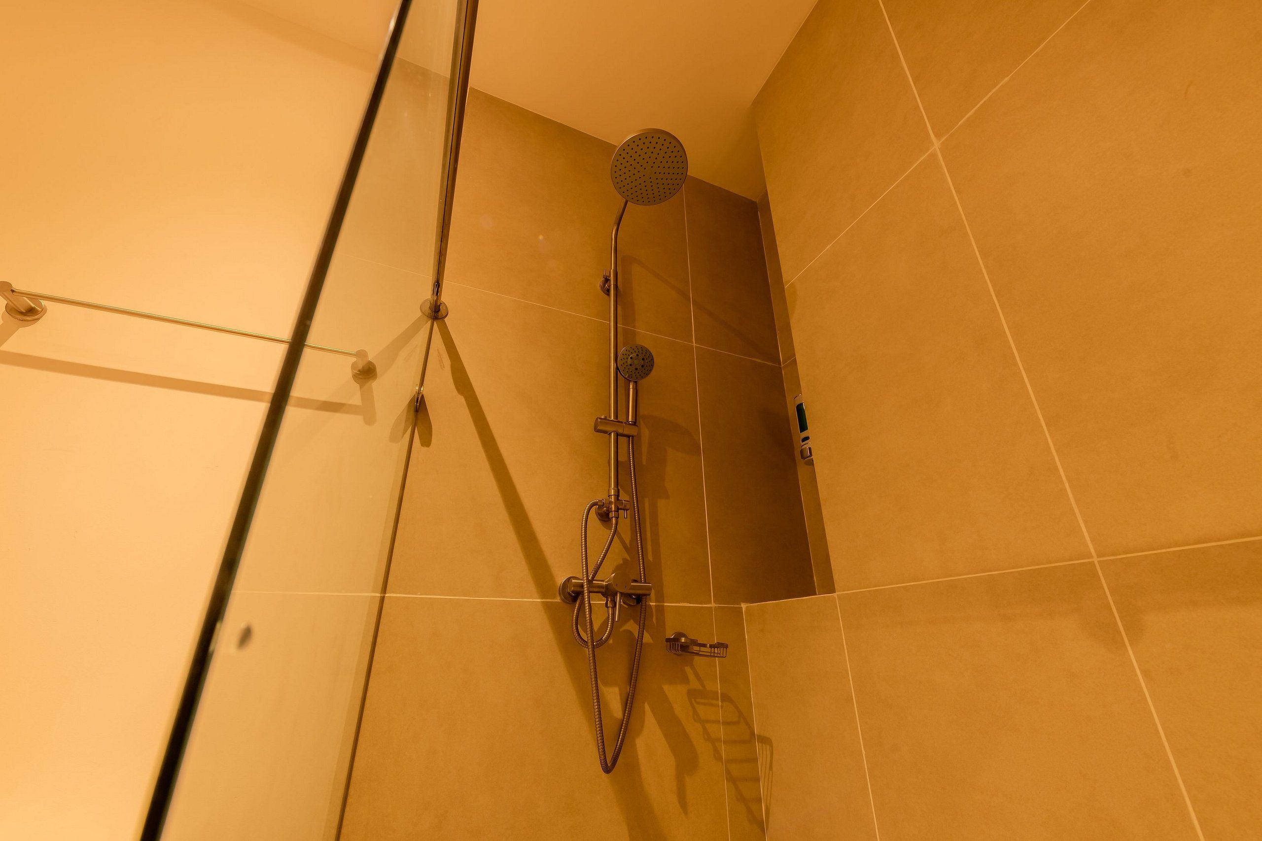 A shower with a handheld showerhead and a wall-mounted faucet.