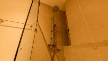 A shower with a handheld showerhead and a wall-mounted faucet.
