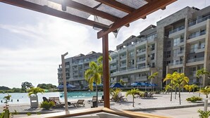 A wooden deck with a hot tub, overlooking a beach and a hotel building. - Apartamento premium en Baia Kristal (Cartagena)
