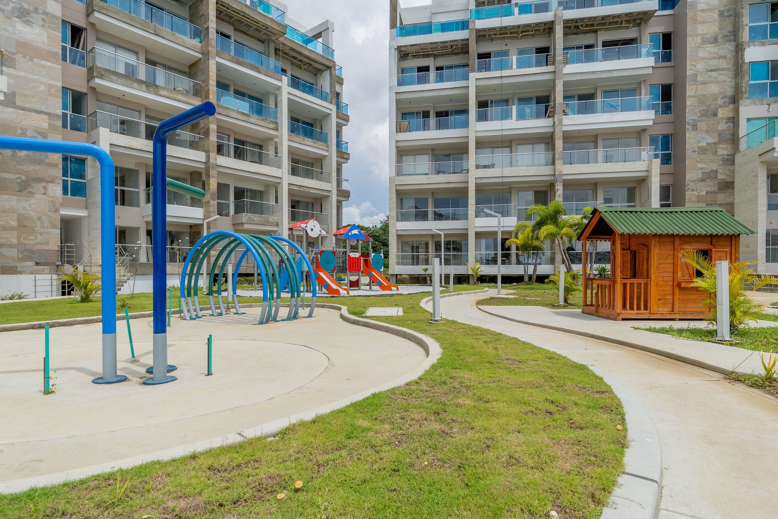 A playground with slides and climbing structures, surrounded by a landscaped area with a walking path.