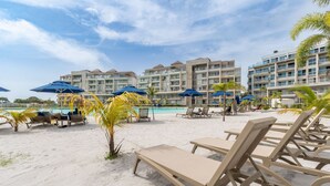 A beachside resort with sun loungers, umbrellas, and a pool. - Apartamento premium en Baia Kristal (Cartagena)