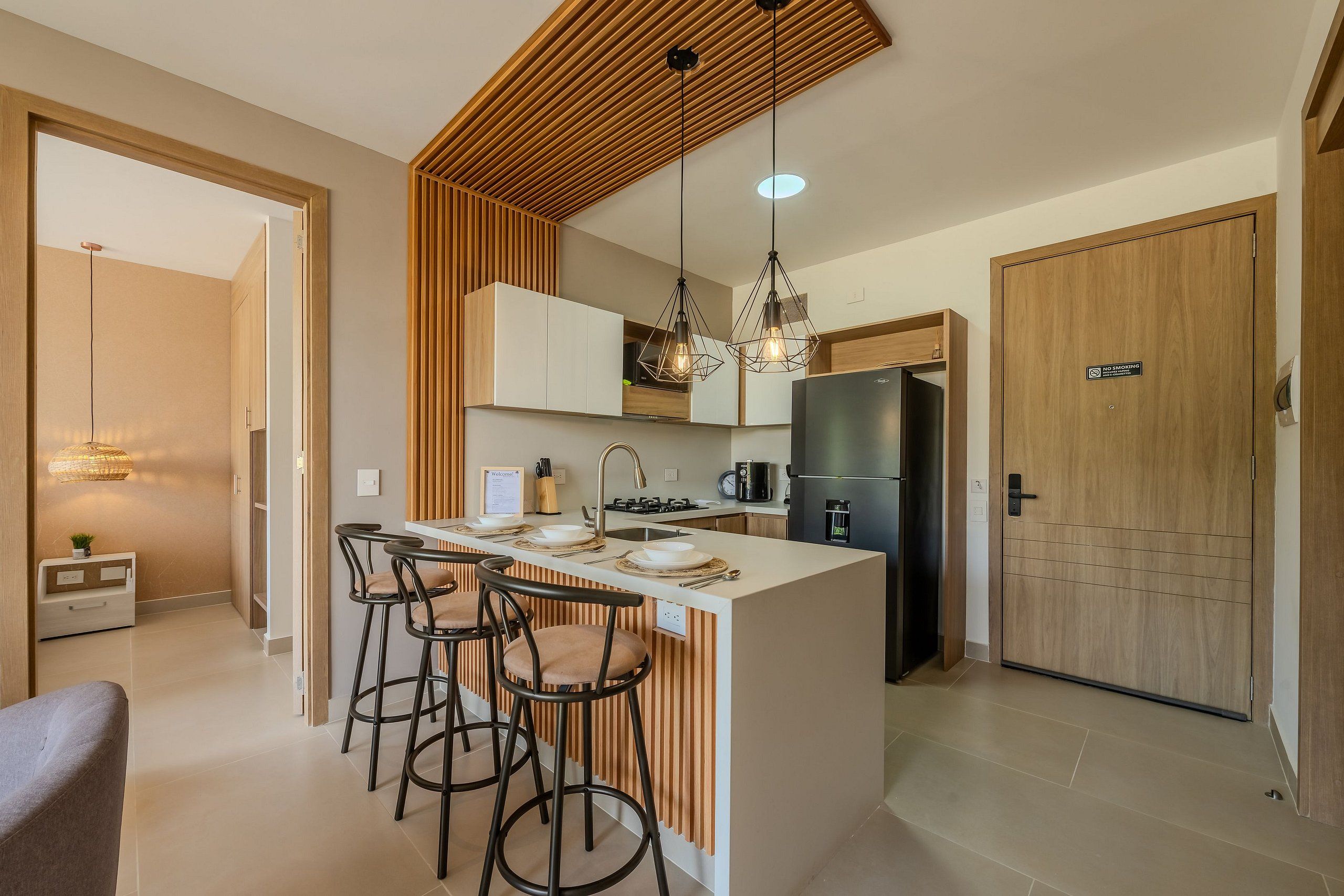 A modern kitchen with a central island, bar stools, pendant lighting, and a built-in oven.