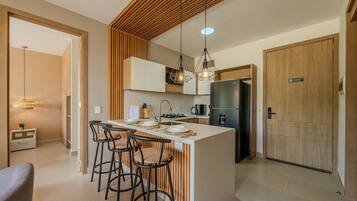 A modern kitchen with a central island, bar stools, pendant lighting, and a built-in oven.