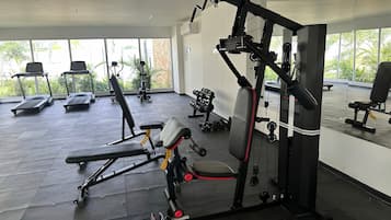 Un gimnasio con cintas de correr, máquinas de pesas y pesas sueltas.