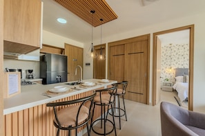 Una cocina moderna con una isla central, taburetes de bar, armarios de madera y techo de madera.