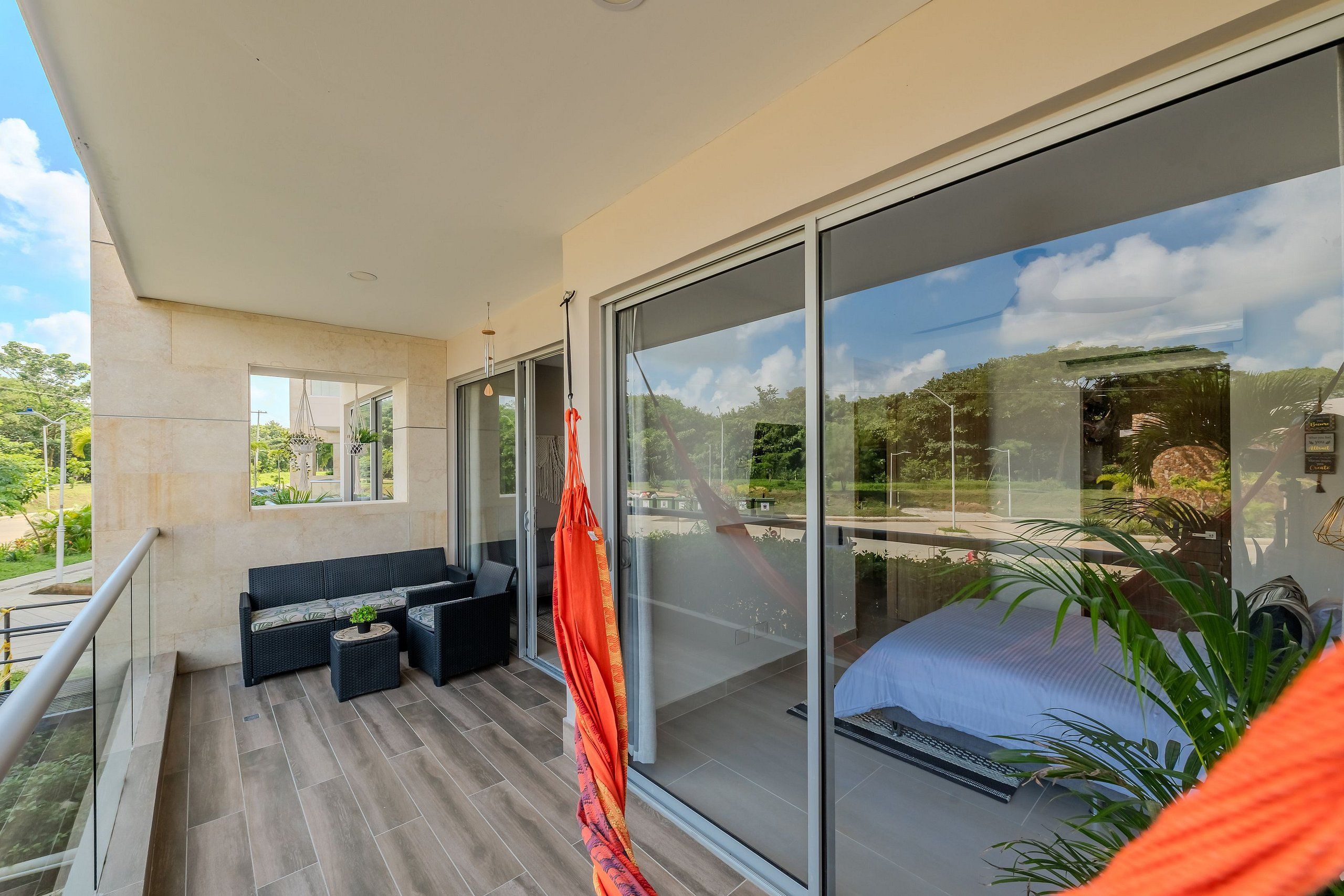 Un balcón con sofá, hamaca y cama, con vistas al exterior.