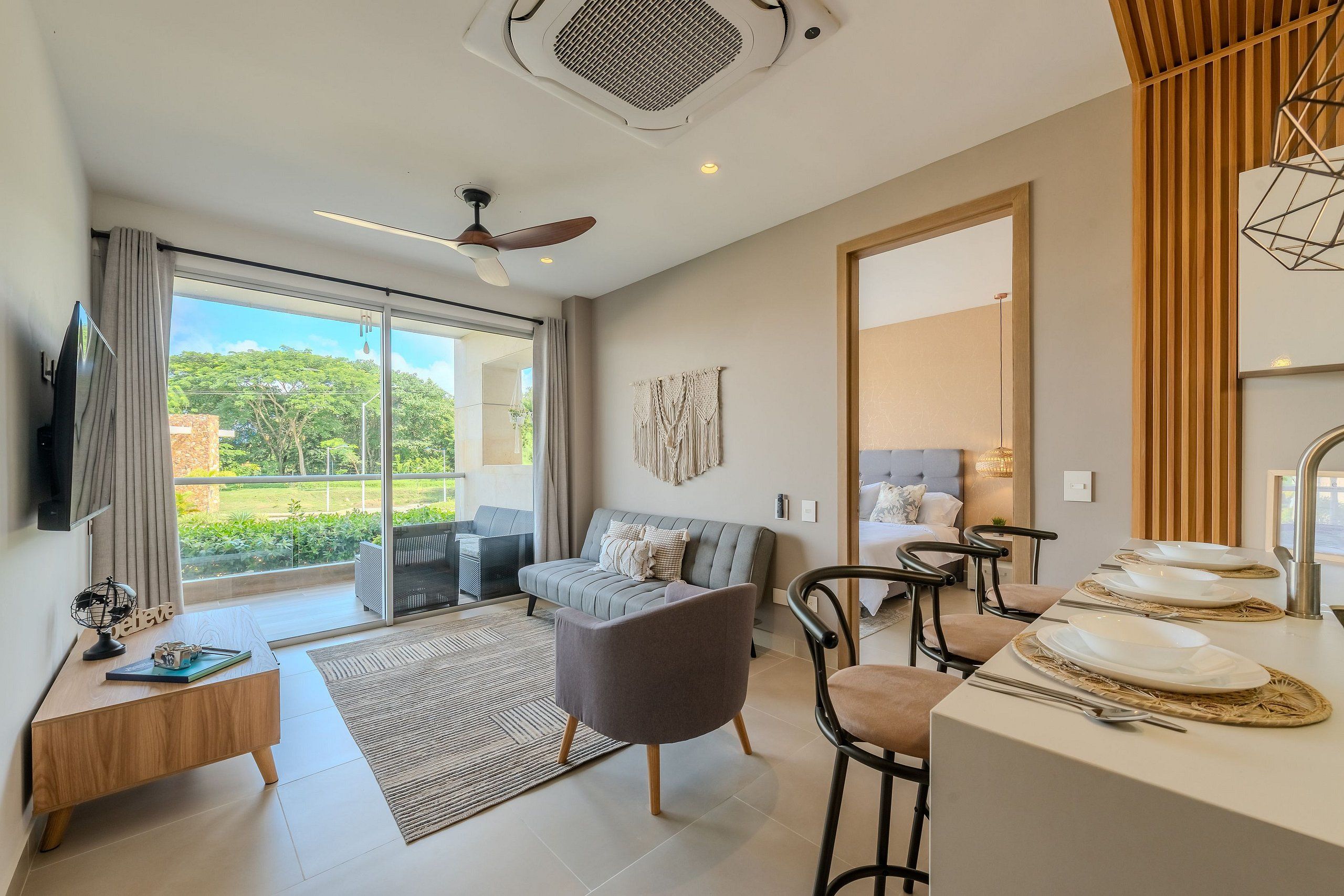 A modern living room with a sofa, a coffee table, and a dining area with chairs and a table set for a meal.