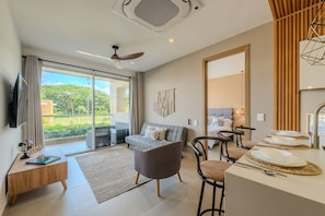 Una sala moderna con un sofá, una mesa de centro y un comedor con sillas y una mesa preparada para una comida.
