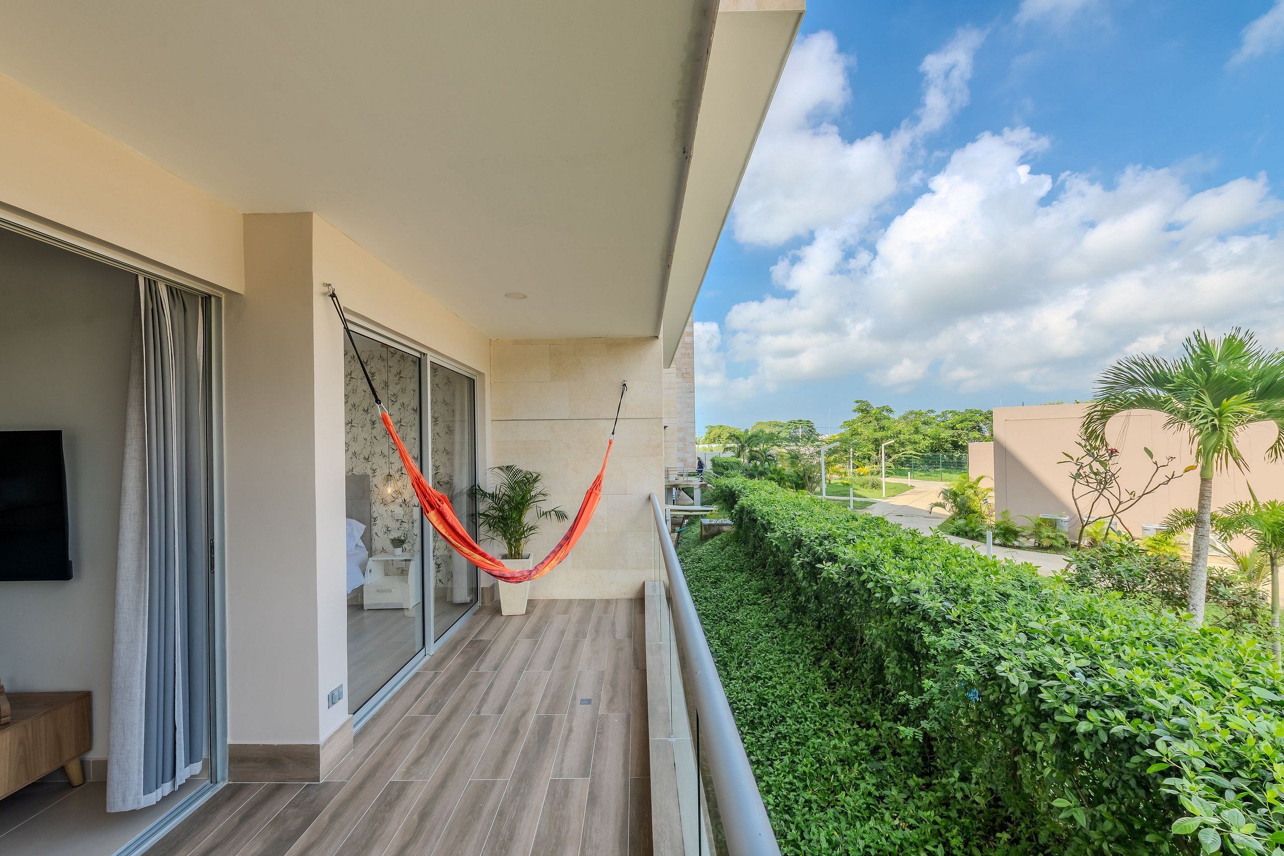 A balcony with a hammock, a TV, and a view of a green landscape.
