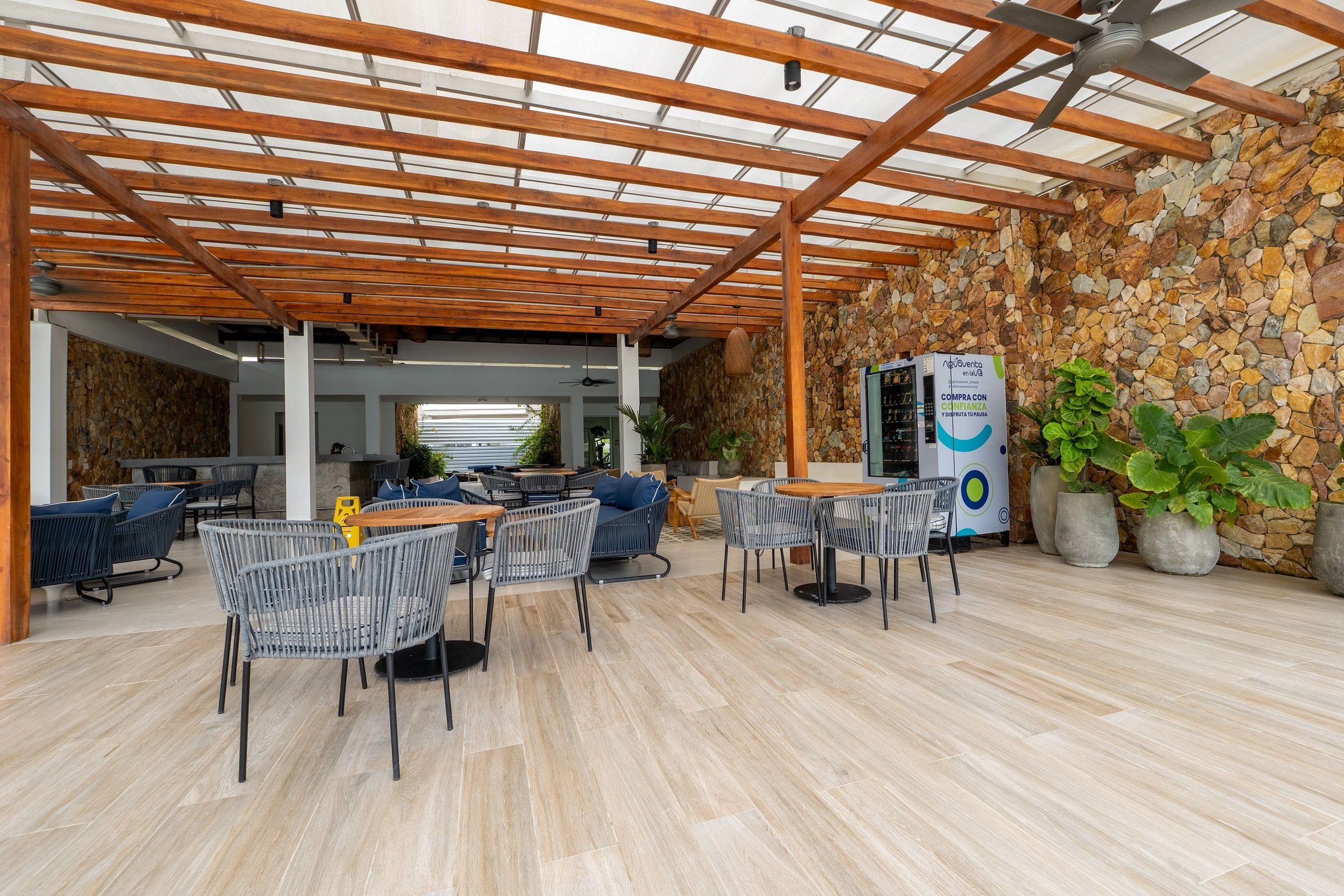 An outdoor patio area with wooden pergola, stone walls, and seating arrangements.